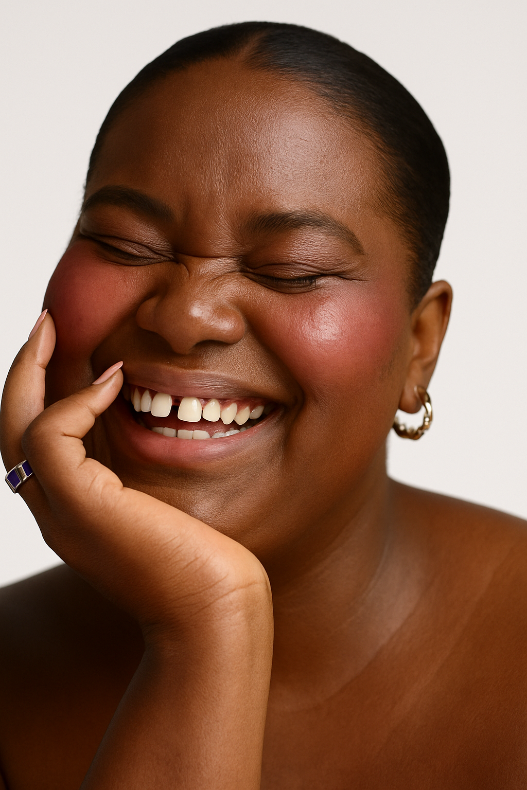 Woman with a joyful expression, smiling broadly with her hand on her cheek.